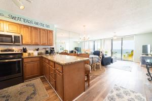 a kitchen with wooden cabinets and a dining room with a table at Seaside Beach Racquet 3504 in Orange Beach