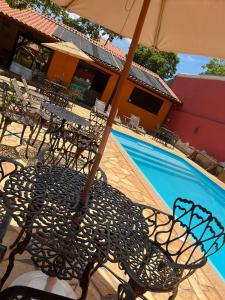 a table and chairs with an umbrella next to a pool at Pousada Flor de Pequi in Serra do Cipo