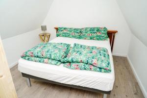 a white bed with green comforter and two pillows at Holiday Dream House-B for 6 Persons in Tornesch