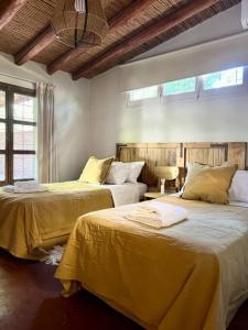 a bedroom with two beds with yellow sheets at Cálida casa en el corazón de Chacras de Coria in Ciudad Lujan de Cuyo