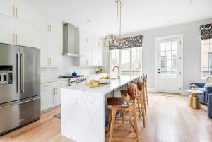 a kitchen with white cabinets and a large island with bar stools at Sky's the Limit in Atlanta