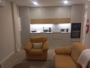 a living room with two chairs and a kitchen at Casinha de Santo Amaro in Ourém