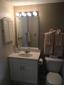 ein Badezimmer mit einem Waschbecken, einem WC und einem Spiegel in der Unterkunft Lake Front Condo with Pool and Hot Tub and Shuffleboard at Lake Ozarks in Osage Beach