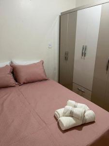 een slaapkamer met een roze bed en handdoeken bij Casa Girassol in Praia Grande