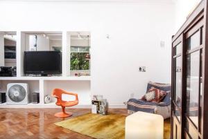 ein Wohnzimmer mit einem TV und einem Stuhl in der Unterkunft 2BR QUIET, STYLISH, GREAT LOCATION in Rio de Janeiro