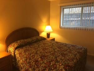 a bedroom with a bed and a lamp and a window at Condo with Pool and Hot Tub at Lake Ozarks in Osage Beach