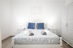 Una cama blanca con almohadas azules y toallas. en Casa da Alexandrina, en Algarvia