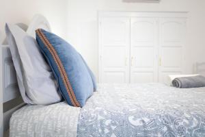 Una cama con almohadas azules y blancas. en Casa da Alexandrina, en Algarvia