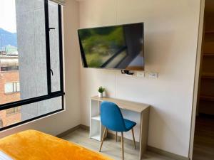 een kamer met een blauwe stoel en een tv aan de muur bij Excepcional loft cerca del Parque La 93 in Bogota