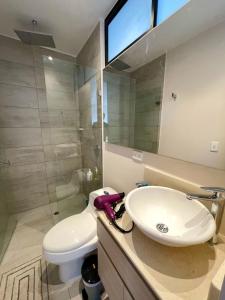 een badkamer met een wastafel, een toilet en een spiegel bij Excepcional loft cerca del Parque La 93 in Bogota