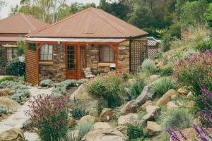 a small house in a garden with rocks and plants at Outdoor Spa & Sauna with amazing views at Jaclyn Studio in Launceston