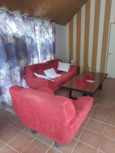 a living room with a red couch and a table at Orchid Island Bure in Pacific Harbour