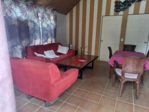 a living room with a red couch and a table at Orchid Island Bure in Pacific Harbour