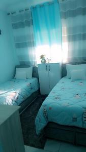 una camera con 2 letti singoli e tende blu di Appartement Basatine a Fes