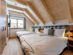 two beds in a room with wooden ceilings at Haus Enzian in Donnersbachwald