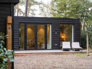 een zwart tiny house met twee witte stoelen bij STEC Tinyhouse in Nunspeet