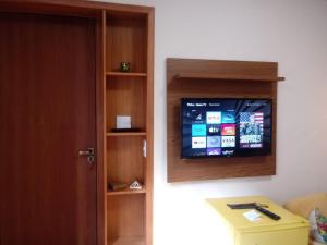 Habitación con TV de pantalla plana en la pared en Apartamento no Condomínio Imperial en Lambari