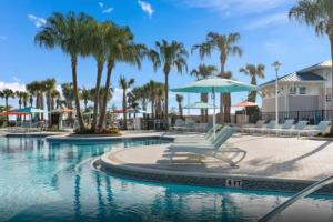 a pool with chairs and an umbrella and palm trees at Luxurious New 9BR Villa w Game Room Theater Pool in Davenport