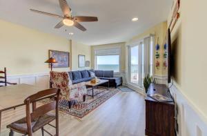 a living room with a couch and a ceiling fan at Carolina Surf - 3BR Condo with Stunning Ocean Views in Carolina Beach