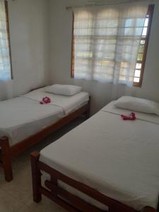 two beds in a room with pink flowers on them at Jilymar Cabaña de descanso, Isla de Barú - Cartagena in Santa Ana