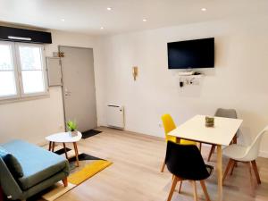 ein Wohnzimmer mit einem Tisch und Stühlen sowie einem TV in der Unterkunft Cozy 2-room 3 min from Mantes train station in Mantes-la-Jolie