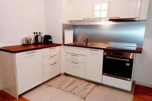 a kitchen with white cabinets and a sink at Elegancia Rueil, 20 min de Paris La Défense, quartier recherché, Lac in Rueil-Malmaison