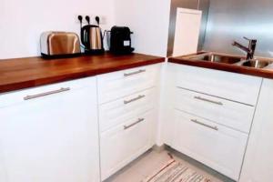 a kitchen with white cabinets and a sink at Elegancia Rueil, 20 min de Paris La Défense, quartier recherché, Lac in Rueil-Malmaison