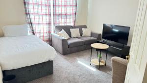 a room with a bed and a couch and a tv at Luxury Living at Hampden Gardens - Stunning Two-Bedroom Flats from Fran Properties in Buckinghamshire