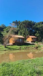 a house next to a body of water at Cabanas da Fazenda / 02 in Gramado