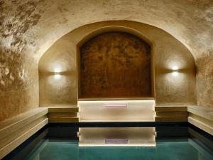 una piscina d'acqua in una stanza con un muro in pietra di Argini Syros a Ermoupoli