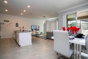a kitchen and living room with red flowers on the counter at Gorgeous 4 Bedroom w Screened Pool Close to Disney 2653 in Kissimmee