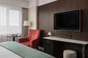 Pokój hotelowy z telewizorem i czerwonym krzesłem w obiekcie Crowne Plaza Dublin Blanchardstown, an IHG Hotel w mieście Blanchardstown