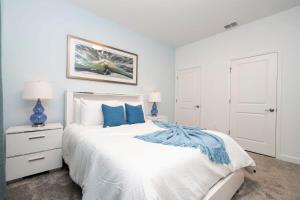 une chambre blanche avec un grand lit avec des oreillers bleus dans l'établissement Marvelous 4Bd w Pool Close to Disney at Storey Lake 2629, à Kissimmee