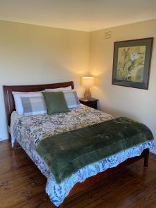 a bedroom with a bed with a green blanket on it at Mount Hope Estate Vineyard in Dixons Creek