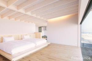 a bedroom with a white bed and a large window at WAKKA in Imabari