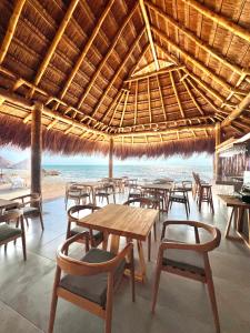 a restaurant with tables and chairs and a straw roof at JERUSALEMA BEACH GLAMPING in Tolú
