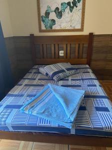 a bed with a blue comforter on top of it at Pousada Familia Aparecida in Aparecida