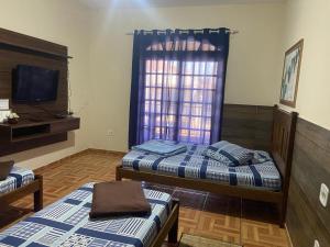 a room with two beds and a television and a window at Pousada Familia Aparecida in Aparecida