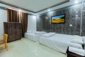 a bedroom with two beds and a tv on the wall at Hotel Trâm Anh in Nhơn Trạch
