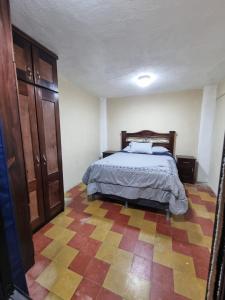 a bedroom with a bed and a checkered floor at El Rinconcito de la Antigua in Antigua Guatemala