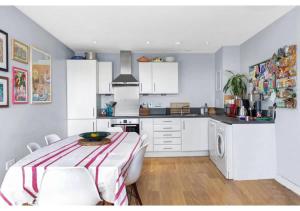 a kitchen with white cabinets and a table with chairs at 2BR Flat at Meath Crescent in London