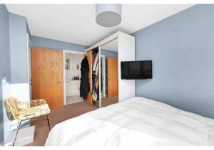 a bedroom with a white bed and a television at 2BR Flat at Meath Crescent in London