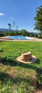 un sombrero sentado en el césped en un campo en Sítio Âmbar - Família, tranquilidade e privacidade, en Lambari