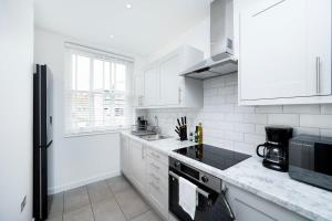 a white kitchen with white appliances and white cabinets at Stylish 3BR Flat in the Heart of Soho London in London