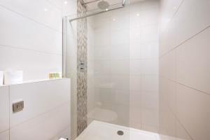 a white bathroom with a shower and a toilet at Stylish 3BR Flat in the Heart of Soho London in London
