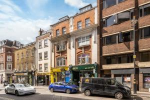 a city street with cars parked in front of buildings at Stylish 3BR Flat in the Heart of Soho London in London