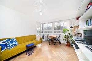 a living room with a yellow couch and a table at Cozy 1 bedroom flat at Earlsferry Way in London