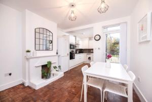 Lovely 2BR house in Norwood Junction London في لندن: مطبخ أبيض مع طاولة ومدفأة