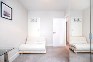 Lovely 2BR house in Norwood Junction London في لندن: سريرين في غرفة بجدران بيضاء