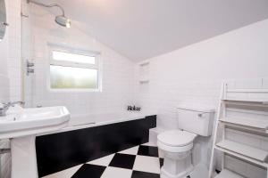 Baño blanco con aseo y lavamanos en Lovely 2BR house in Norwood Junction London, en Londres